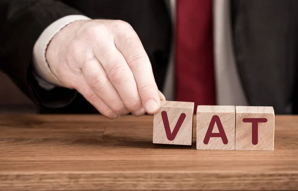 Value added tax or VAT concept with an accountant or businessman creating the word VAT from letters with copy space