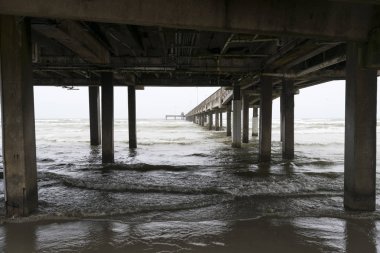 Okyanus dalgaları sahilde uzun bir iskele altında üzerine haddeleme