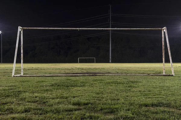 Empty soccer field at night through goal without net