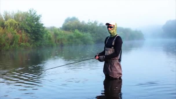 Pescador va a pescar con mosca en la niebla del río mañana — Vídeo de stock