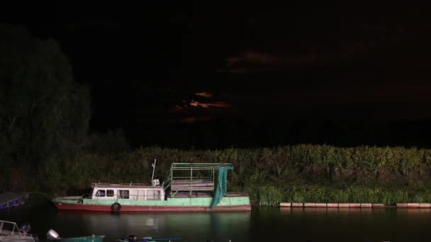 Vista notturna di un porto con la vecchia barca e una luna che sorge sullo sfondo. Tempo di decadenza 1080p — Video Stock