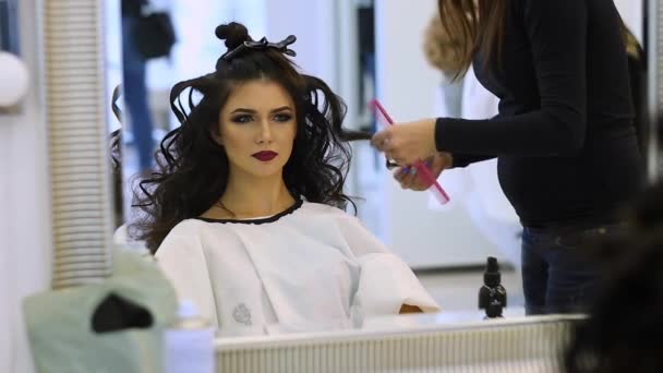 Frisör gör håret klä vacker flicka i en skönhetssalong — Stockvideo