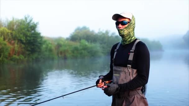 Pescador va a pescar con mosca en la niebla del río mañana — Vídeos de Stock