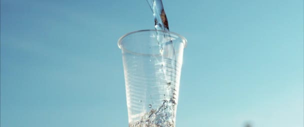 Agua que fluye en la taza de plástico. Enfriador de agua. Primer plano de la taza de mano con agua. Agua mineral vertiendo en taza transparente y desbordamiento — Vídeo de stock