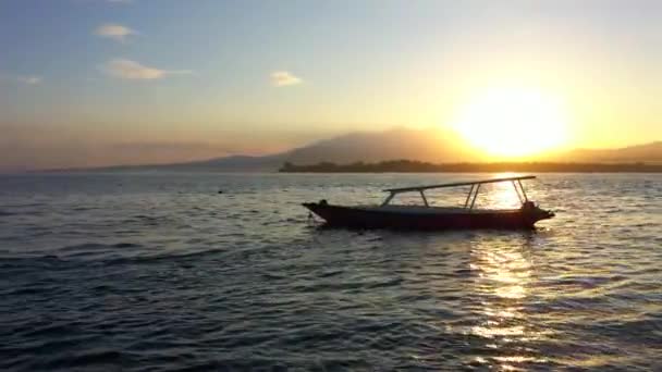 Vista drone do nascer do sol sobre o oceano com um barco e montanhas no backgound. Indonésia, Gili Air, 2020 — Vídeo de Stock