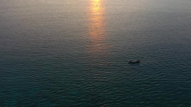 Vista aérea do drone do oceano com barco de pesca à deriva sobre o pôr do sol incrível refletindo em uma água . — Vídeo de Stock