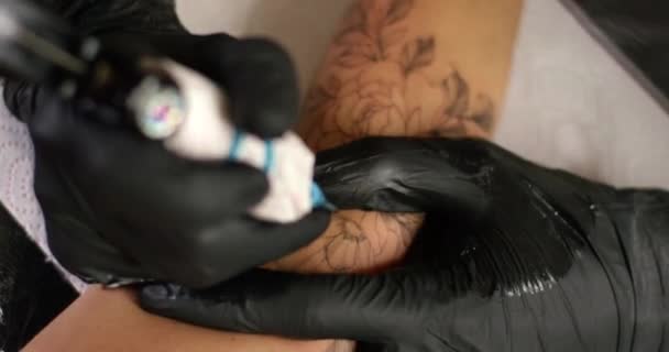 Közelkép tetováló művész csinál egy tetoválás egy női kéz géppisztoly festék felhívni. — Stock videók