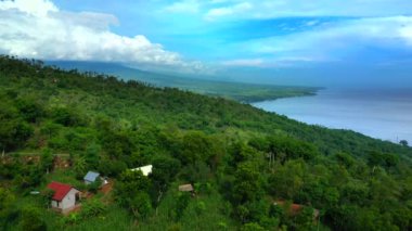 Arka planda büyük bir vadi ve bir ocaen olan dağdaki küçük bir köyün havadan görünüşü. Bali, Endonezya.