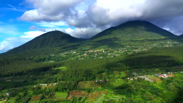 Vista aérea Los picos de las montañas están cubiertos de bosque tropical bajo las nubes. Lago, montaña, nubes, cielo azul, Bali, Indonesia. Paisaje de montaña. Vídeo 4K. Concepto de viaje Imágenes aéreas — Vídeos de Stock