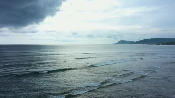 Vista aérea de una puesta de sol detrás de nubes grises oscuras. Volando lentamente sobre el agua oscura del océano . — Vídeos de Stock