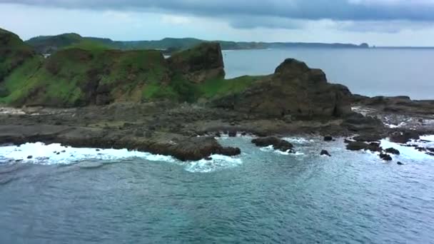 Аерофотозйомка морських хвиль, що розбиваються і вражають кам'янисті камені. Океанічні хвилі розбризкують і створюють піну . — стокове відео