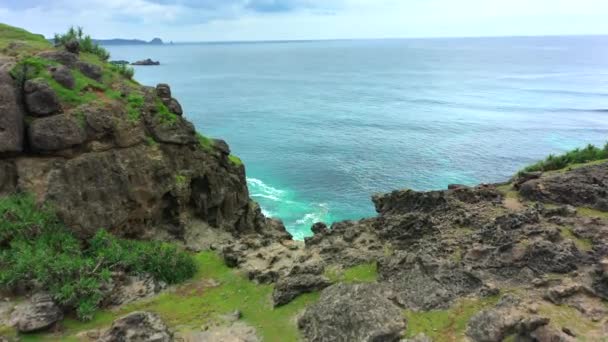 Rotsachtige kust van de zee met golven op de achtergrond. Zonnige dag in Lombok, Indonesië. — Stockvideo