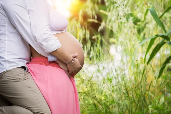 Adam hamile karısını göbek kucaklayan.