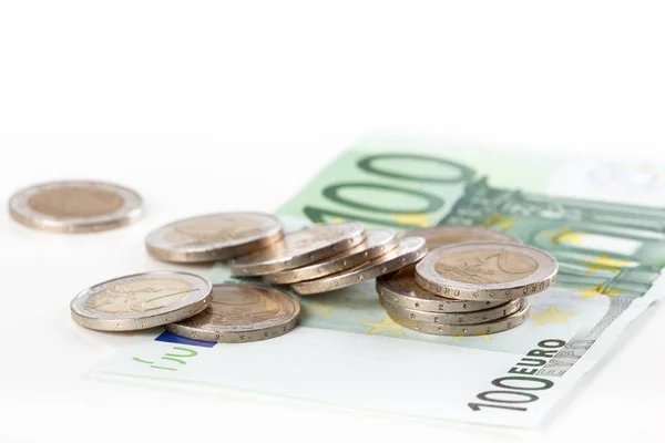 Primer plano de un billete de cien euros y monedas en euros sobre fondo blanco — Foto de Stock