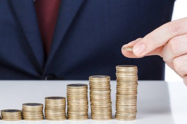 İşadamı el yığın bir euro sikke sütun artan içine