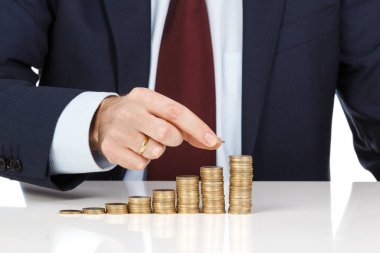 İşadamı el yığın bir euro sikke sütun artan içine