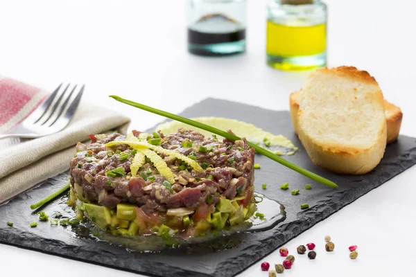 Mavi yüzgeçli tuna tartare avokado ile siyah arduvaz tabakta.