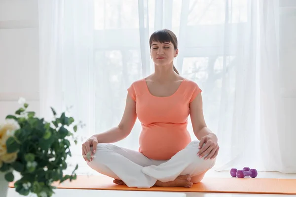 Pembe tshirt yoga ile bir Avrupa hamile kadın onu carehealth için egzersizler ve doğmamış çocuğunu gün zaman ışık yatak odasında