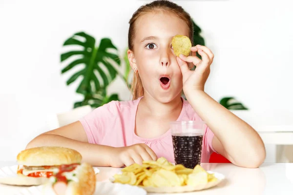 Junges süßes europäisches Mädchen im T-Shirt isst ungesundes Essen wie Hot Dog und Chips — Stockfoto