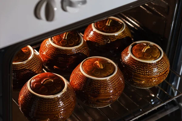 Six marmite chaude en céramique d'argile brune avec des aliments soutenus ou cuits à l'intérieur du four — Photo