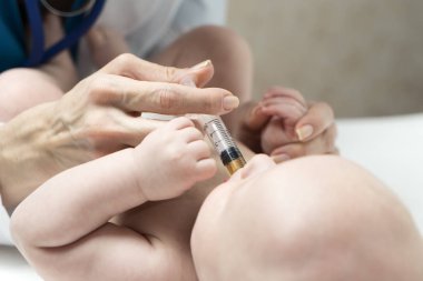 Bir beyaz kadın doktor sıvı ilaç bazı doz erkek bebek bebek şırınga tarafından ağız içine hastalık veya aşı randevu için veriyor.