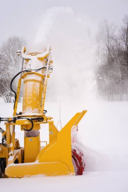 Beyaz kar güçlü bir akım giderken yolun büyük sarı kar vidalı ve sarmal temizlik