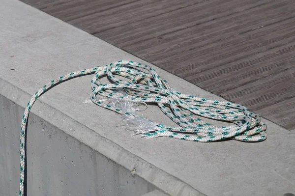 Coiled mooring line tied around cleat on a wooden dock. — Stock Photo, Image