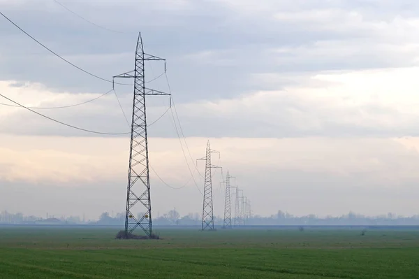 De lijn van de macht in de mist. Hoogspanning bij zonsopgang. Mistige ochtend — Stockfoto