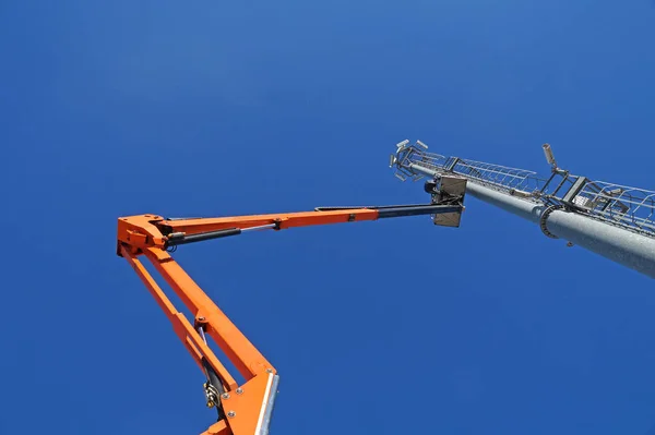 Plataforma de construcción móvil hidráulica elevada hacia un cielo azul con poste de metal lámpara de calle —  Fotos de Stock