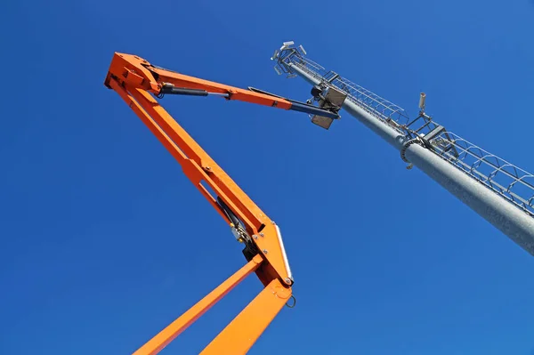 Piattaforma idraulica mobile da costruzione elevata verso un cielo blu con lampione in metallo — Foto Stock