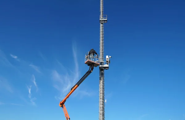 Hydraulische mobiele bouw platform verhoogde naar een blauwe hemel met metalen paal straat lamp — Stockfoto