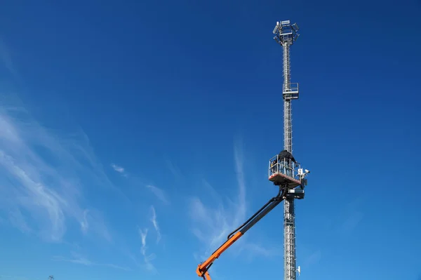 Гидравлическая передвижная строительная платформа, возвышенная к голубому небу с металлическим фонарем — стоковое фото