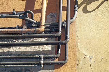 Su ve gaz boru hattı eski bir tuğla duvarın önünde.