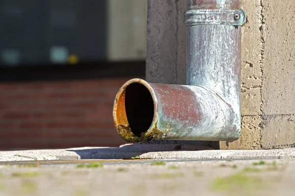 Regengoot aftappen van water uit de buurt van een dak. — Stockfoto