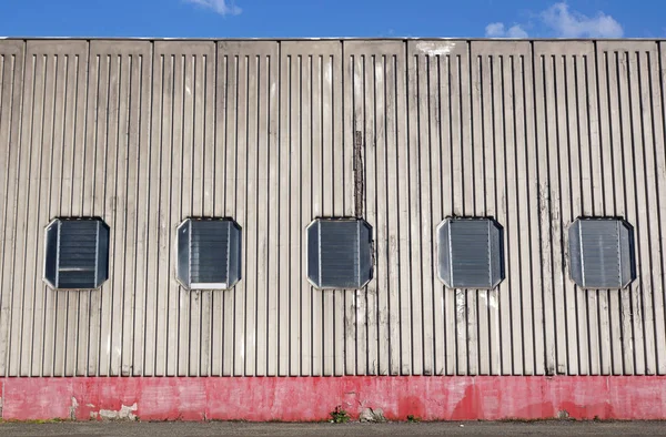 Architectural close up of an industrial facade building with metallic panels and windows