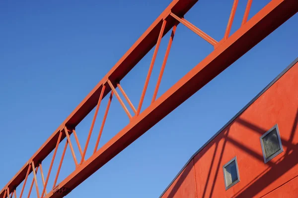 Стальной луч конструкции, указывающий на голубое небо с красным фасадом — стоковое фото