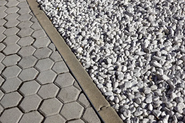Grå färgade runda stenar bredvid en konkret trottoaren — Stockfoto