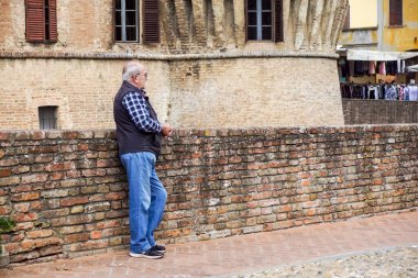 Parma, İtalya - Nisan 2017: yaşlı bir adamın tuğla duvara yakın bekler