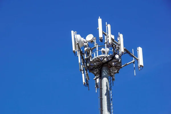 Partie supérieure de la tour de communication de téléphone portable avec plusieurs antennes contre un ciel bleu — Photo