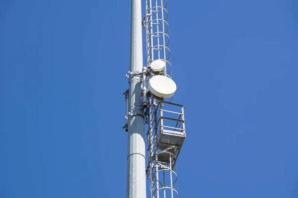 Outdoor stadium lights and telecommunication tower against daytime blue sky. — Stock Photo, Image