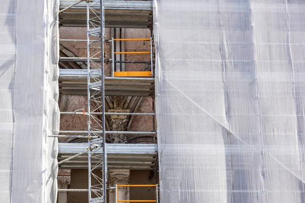 Außenfassade des Mehrfamilienhauses wird mit Gerüsten und grünem Netz saniert — Stockfoto