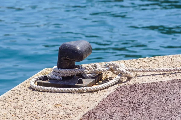 Gammal metallbrygga förtöjningsstolpe med ring och rep för att säkra fiskebåtar — Stockfoto