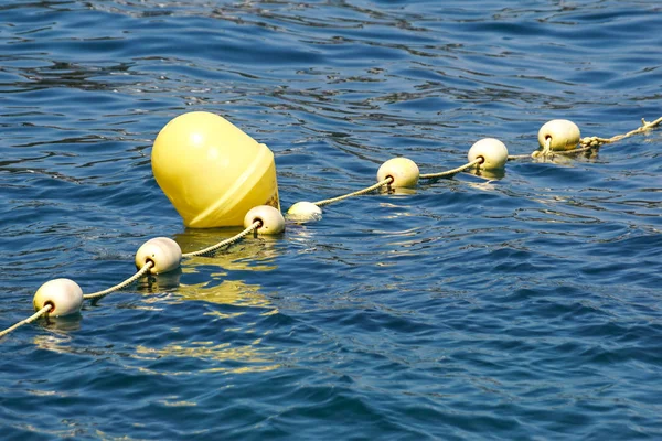 Line of yellow buoys against the blue sea. Restriction on open water. Glare and ripples on the water — Stock Photo, Image