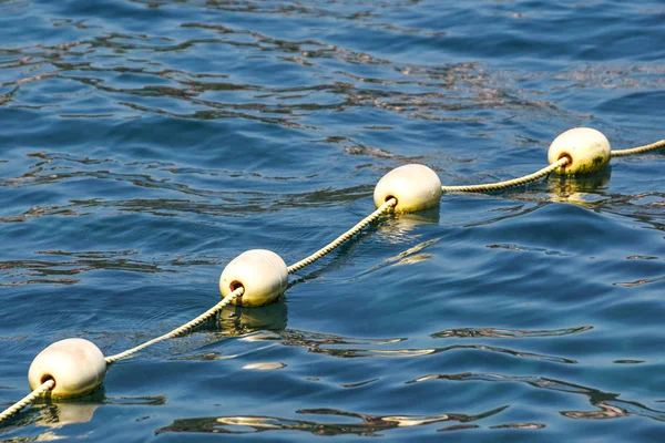 Linea di boe gialle contro il mare blu. Restrizione sull'acqua aperta. Riverbero e increspature sull'acqua — Foto Stock