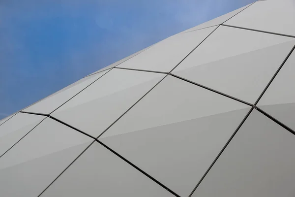 Detail of a circular facade of a modern building made of sandwich panels on blue sky background.