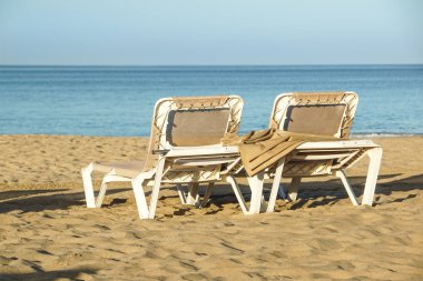 Şezlonglar ve bir tatil beldesi, yaz tatili günbatımında sakin ve rahat atmosferinin, kapalı şemsiye