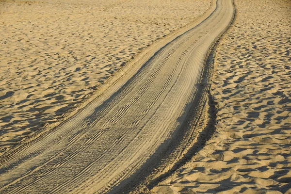 日落时进入大海的金沙上的铁轨 — 图库照片