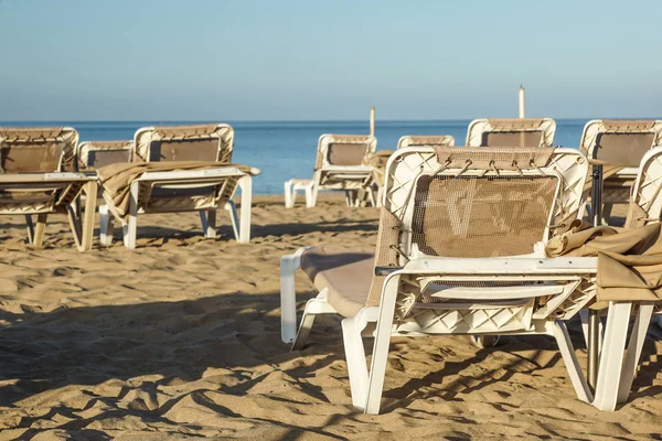 Chaises longues et parasols fermés dans une station balnéaire, l'atmosphère calme et détendue des vacances d'été au coucher du soleil — Photo