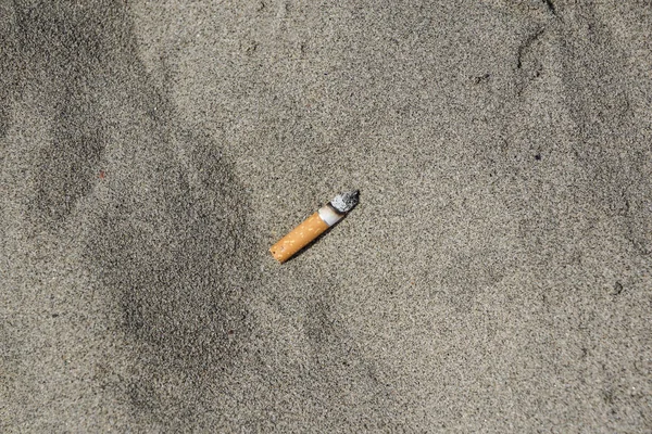 Cigarrillo en arena playa contaminación basura — Foto de Stock