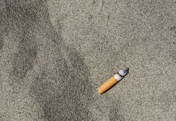 Cigarrillo en arena playa contaminación basura — Foto de Stock